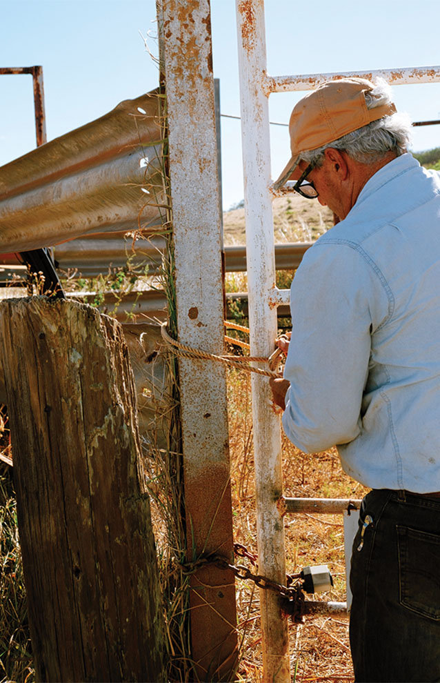 old man stands by a gate to unlock the entrance. 